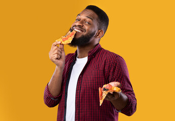 Black Guy Enjoying Eating Tasty Pizza Standing Over Yellow Background