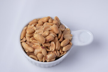 Peanuts in a white ceramic cup on a white background