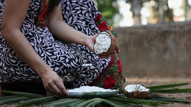Woman hand grating fresh raw coconut cut open in half 4K slow motion video , footage of Indian Kitchen , Kerala India. coconut organic coconut farm, fresh grated coconut for making coconut milk , oil
