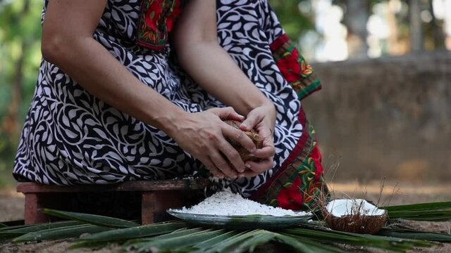 Woman hand grating fresh raw coconut cut open in half 4K slow motion video , footage of Indian Kitchen , Kerala India. coconut organic coconut farm, fresh grated coconut for making coconut milk , oil