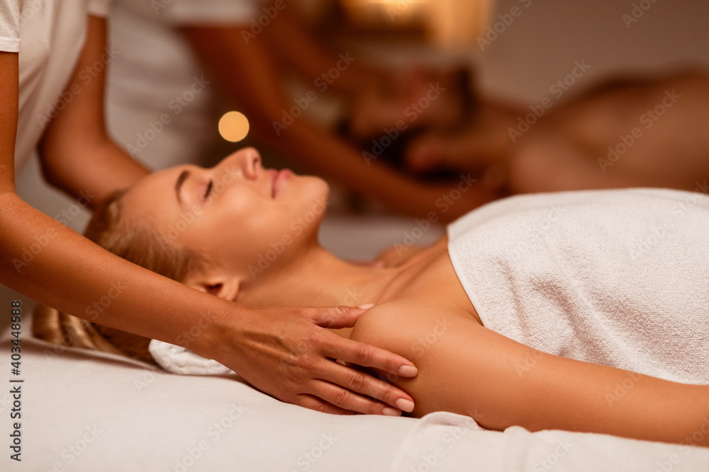 Poster woman enjoying massage during couples beauty treatment lying at spa