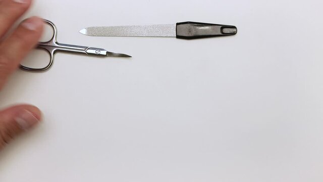 We put scissors, clipper, extractor, nippers, nail files on the table. Demonstration of tools for manicure. Items for work on a light surface. Professional hand care. Isolated video.