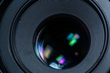 Beautiful camera lens with geen and pink light of glass on a black background. Macro photography...