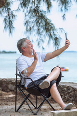 Fototapeta premium senior elder take vdo call with mobile, he is very happy and smile in outdoor background.