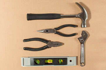 Essential basic tools set consisting hammer, pliers, level  and wrench isolated on cardboard paper