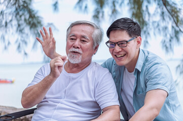 Asian young man take care and warn hug father, he is very happy and smile in outdoor  background.