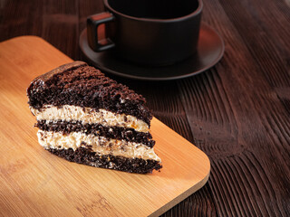 Piece of chocolate cake on wooden plate and black wooden table. Homemade bakery concept for birthday cake or valentine dessert.