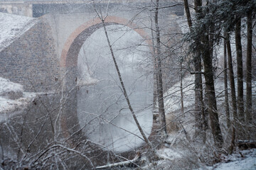 zabytkowy kamienno ceglany most na rzeką w śnieżną zimę