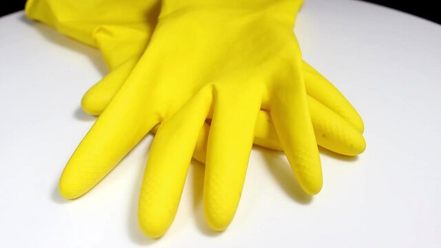 Yellow household gloves on a white background. Turntable. Selective shot.