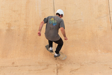 Young man skater wearing a white helmet doing a trick on a skateboard