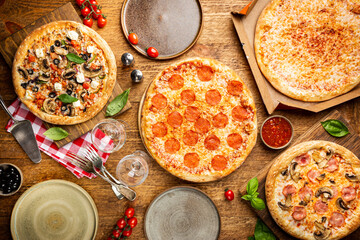 Family or friends pizza party. Flat-lay of different types of pizza and red wine over rustic wooden table, top view.