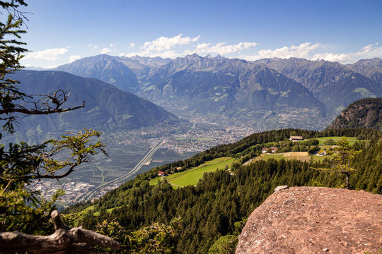 Panoramic high angle view over city of Merano and mountain range Texelgruppe seen from iconic view point "Knottnkino" in V&ouml;ran, South Tyrol, Italy on sunny summer day