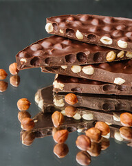 Pieces of milk chocolate with hazelnuts on a dark background, handmade chocolate