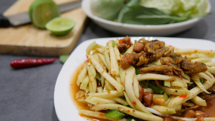 Yum, mango photo top views Food arrangement. Spicy salad food, topped with fried nuts and crispy fish. The main ingredients are raw mango, lime juice, fresh chili powder, fish sauce, sugar to mix.