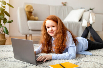 Girl lying on floor carpet and using her laptop computer