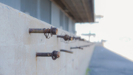 Bolt and screw are embedded in cement wall. Rusted nut embedded in the cement stand At the warehouse