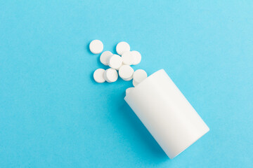 White tablets and bottle for tablets on blue background