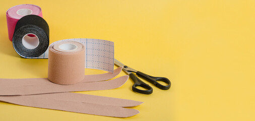 Kinesiological multi-colored tapes for fixing muscles during sports and after injuries on a yellow background with copy space.