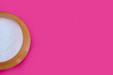 Cosmetic cream in a jar on a pink background, topview. Copy space for text