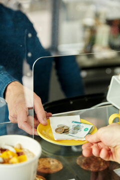 Close up of hands exhanging plate with money for payment in cafe