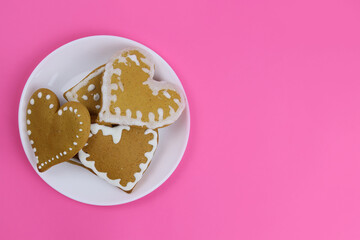 Gingerbread cookies hearts in a white plate on a pink background