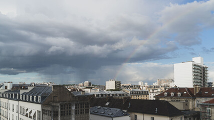 Fototapeta na wymiar Panorama sur les toits de paris, un arc-en-ciel traverse le ciel, des nuages sombres, il pleut.