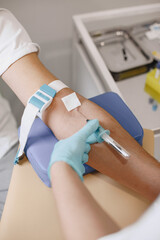 Skillful nurse is doing blood test for man in clinic. Man in a medical mask.