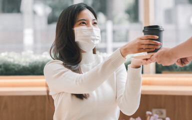 Woman wearing mask and pick up coffee served by a waiter