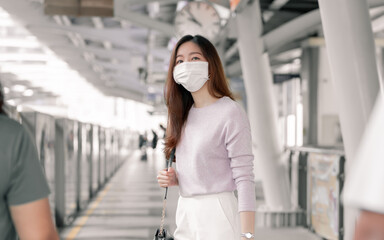 Woman wearing face mask and waiting for a train while standing on railway station