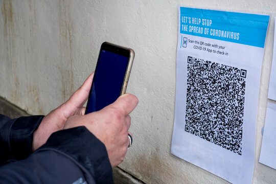 Close-up of person with smartphone scanning QR code in conjunction with the Covid-19 app.