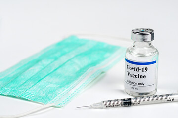 COVID-19 vaccine bottle, vials, syringes and face mask on white background with copy space. Vaccination session and immunity improvement.