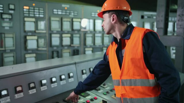 Engineer wearing an orange protective mask, hand finger press button controling cnc machine, workers operating factory machinery in warehouse machinery factory.