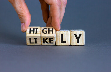 Highly likely symbol. Hand turns the wooden cube with words 'Highly likely' on a beautiful grey...
