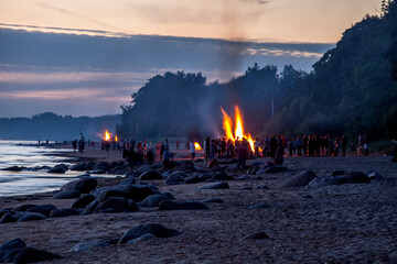 Unrecognisable people celebrating summer solstice with large bonfires on Baltic Sea sandy beach