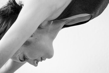 Close-up of a young woman with open eyes performing the Adho Mukha Svanasana or downward-facing dog, one of yoga's most widely recognized yoga poses. Black and white horizontal view.