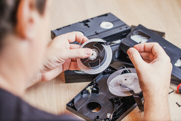 Disassembled old video cassette with tape in the hands of the master. Outdated technology.