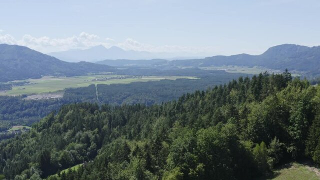 Wide-angle aerial drone shot of beautiful distance landscape and forest at front. Lavamünd, Austria.