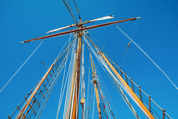 Old sailing ship wood mast, rigging of a sailing ship detail against blue sky