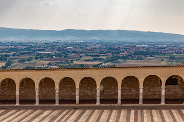 Colonnade of Piazza Inferiore in Assisi and view of the valley