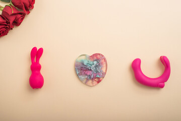 Rose heart and clitoral vibrator on a beige background. Flat lay