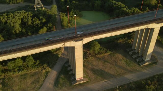 Aerial high angle shot flying over traffic driving on Zarate Brazo Largo bridge at golden hour