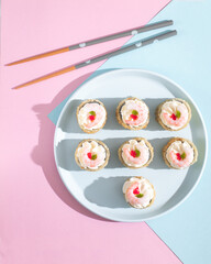 Japanese sushi roll on cute pink and blue background with chopsticks top view