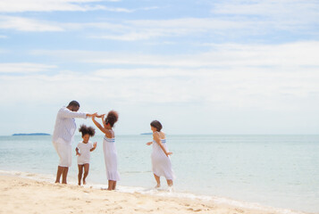 Fototapeta na wymiar Happy African American family, father, mother and daughters happiness vacation relax with sea background.Parents with children enjoying vacation on beach.