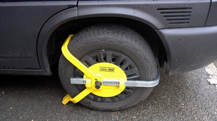 Europe, Italy, mIlan January 2021 - car wheel blocked by a yellow tool - security against theft and fine, fine for parking in an unsuitable area