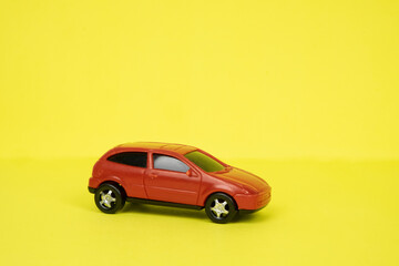 Toy red car close-up on a yellow background. Place for text