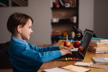 A Preteen boy uses a laptop to make online classes. E-Education Distance Learning, Home Schooling.