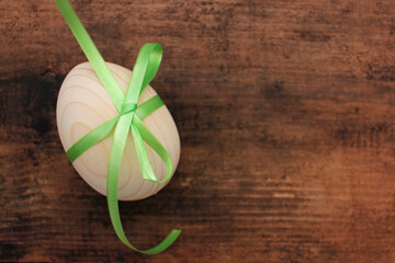 Blank wooden easter egg tied with green ribbon for painting or decoupage on wood background. Top view