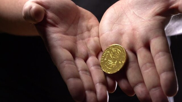 Slow Motion. Pour Gold Coins from Hands. Hands With Gold Coins on Black Background.