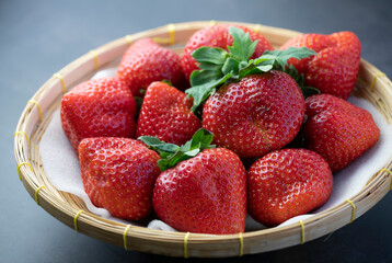 Fresh strawberries in a wooden bowl on  black table, Red Strawberries in Bamboo basket.