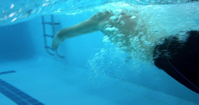 Paralympic professional amputee swimmer butterfly swimming underwater in indoor pool